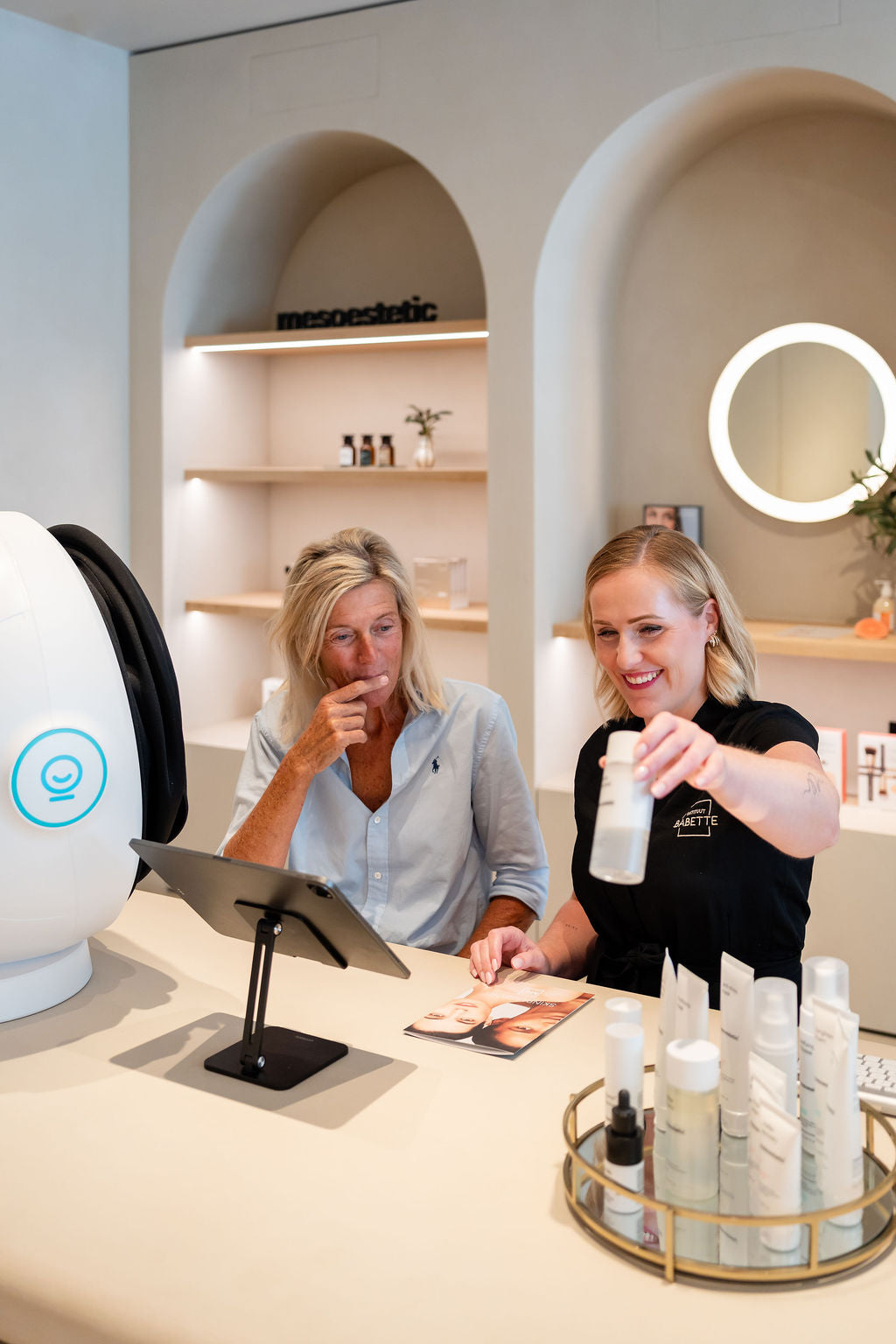 Babette geeft advies aan een klant aan de analysetafel, met de Eve M en de mesoestetic-wand